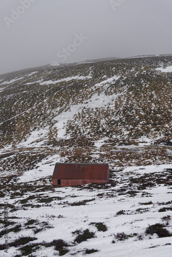A small abandoned Corrugated Tin mountain Bothy high up on the slopes of the Glens Ski Area beneath the Cairnwell Mountain on a snowy day. photo
