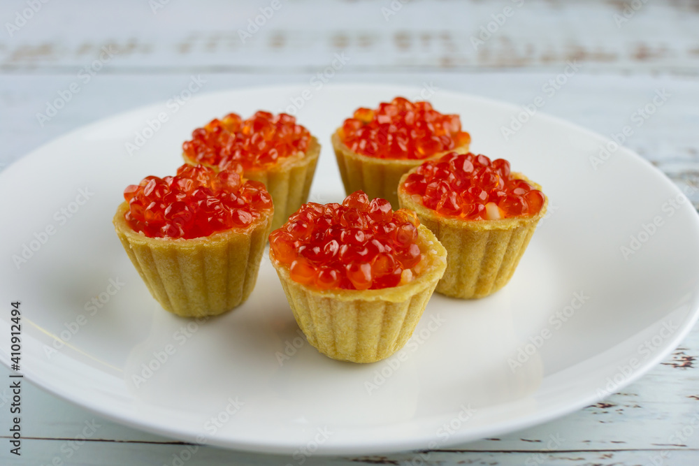 tartlets with red salmon caviar on a white plate, delicious appetizing baskets with eggs close-up on a white background tartlets with red salmon caviar on a white plate, delicious appetizing baskets with eggs close-up on a white background