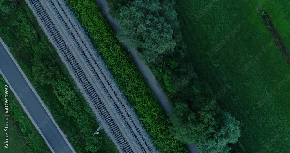Aerial overhead top view of drone flying above railway tracks. Double railroad and narrow countryside road near. Rail made between farming fields Aerial overhead top view of drone flying above railway tracks. Double railroad and narrow countryside road near. Rail made between farming fields