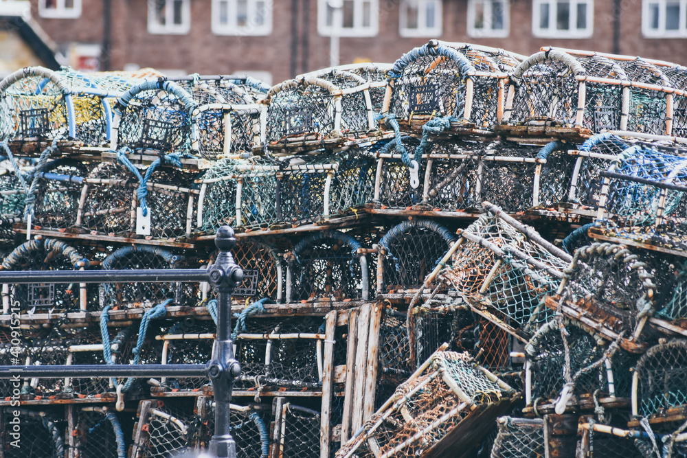 Obraz premium Lobster and crab pots traps stacked on harbour. Fishing industry in Whitby, England, United Kingdom.