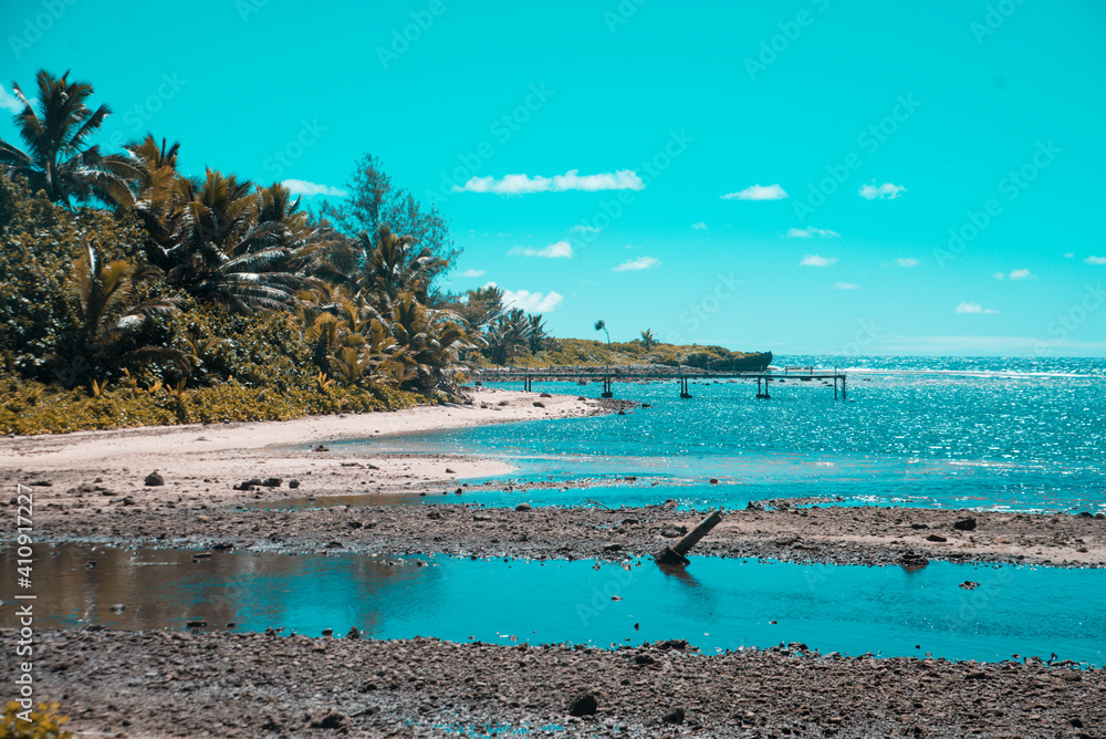 View of a beautiful tropical beach with white sand, palm trees, turquoise ocean with clouds on sunny summer day. Perfect landscape background for relaxing vacation, Rarotonga, Cook Island.