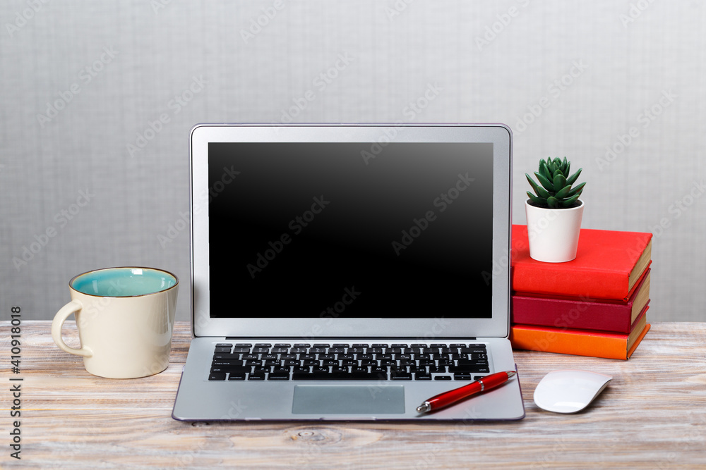 Laptop with blank screen, cup of coffee and books or notebooks on a wooden table. mockup for your text Laptop with blank screen, cup of coffee and books or notebooks on a wooden table. mockup for your text