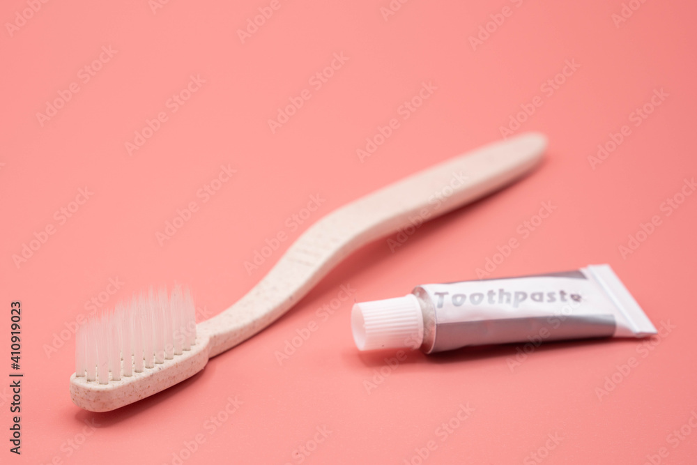 Natural toothbrush with toothpaste on pink background.