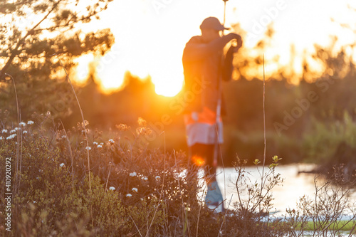 man making photo on SUP stand up paddle boarding at sunset in lake. Summer evening activity