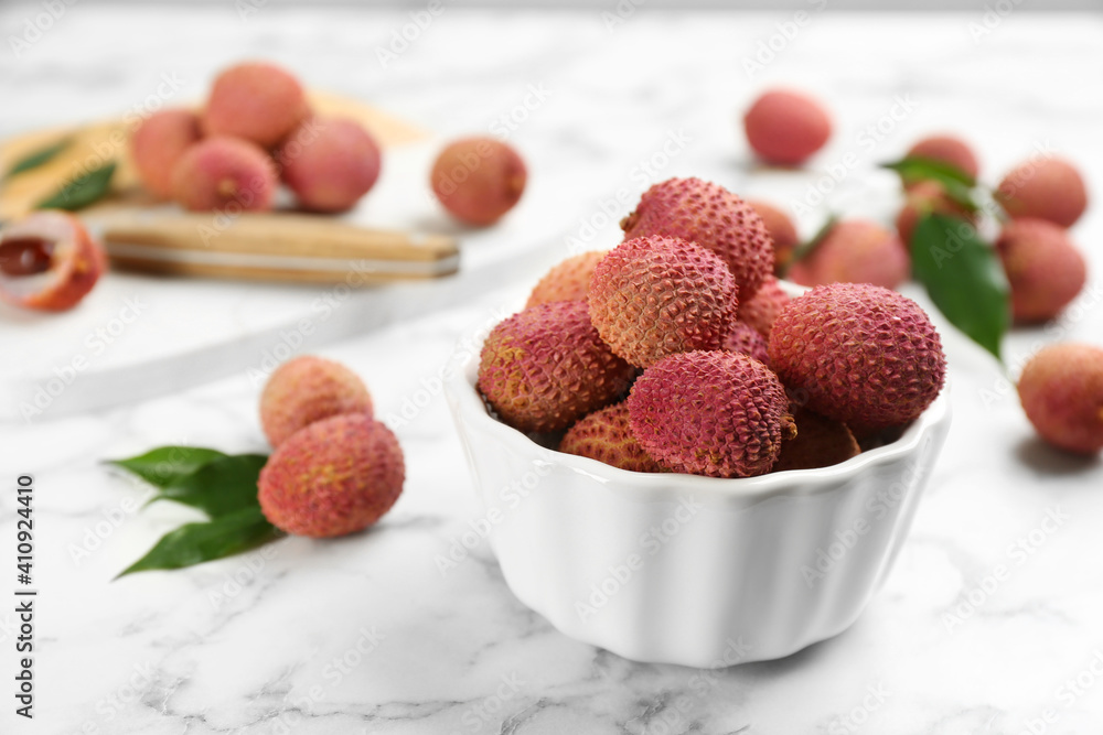 Fresh ripe lychee fruits in ceramic bowl on white marble table. Space for text Fresh ripe lychee fruits in ceramic bowl on white marble table. Space for text