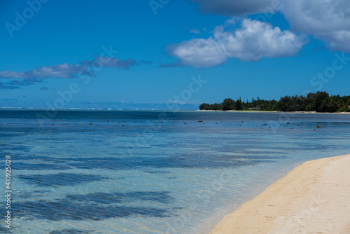 View of a beautiful tropical beach with white sand, palm trees, turquoise ocean with clouds on sunny summer day. Perfect landscape background for relaxing vacation, Rarotonga, Cook Island.