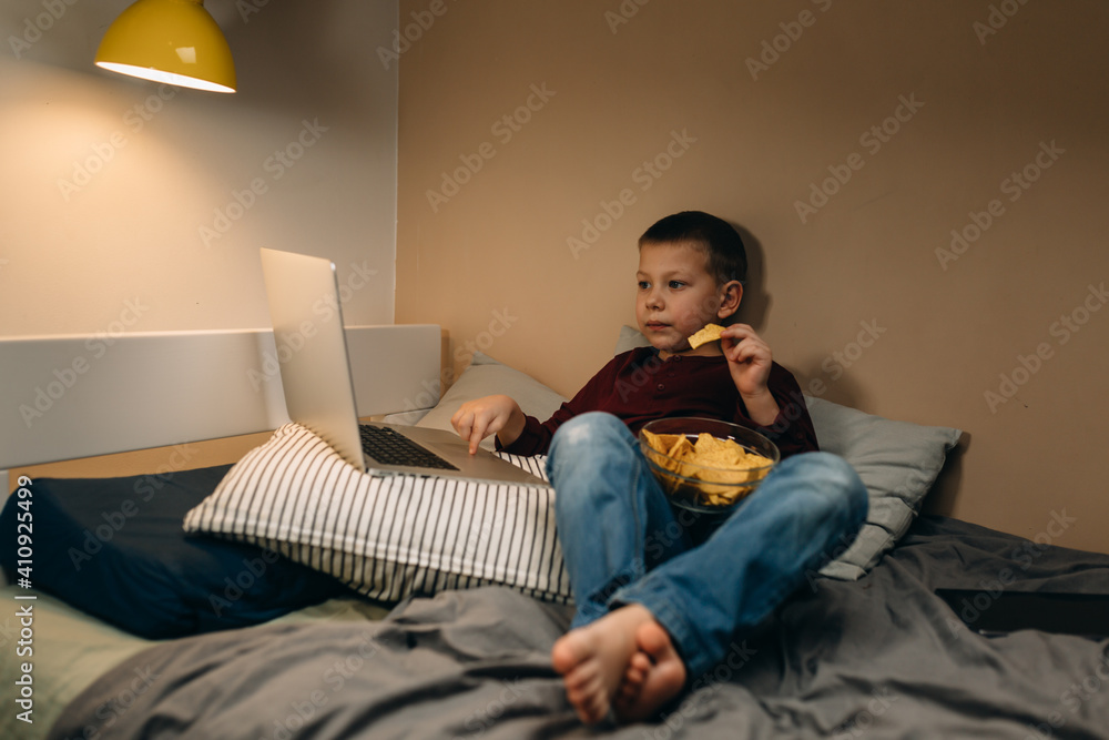 young boy eating unhealthy and using laptop or digital tablet young boy eating unhealthy and using laptop or digital tablet