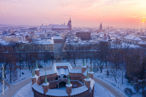 Barbikan and Krakow Old Town in winter. Snow on roofs in winter Krakow Poland at sunset. Medieval Barbacan fortification, Royal Road and city center. photo