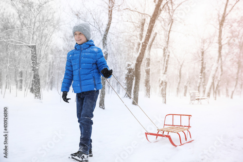 Cute little boy with sleigh outdoors on winter day