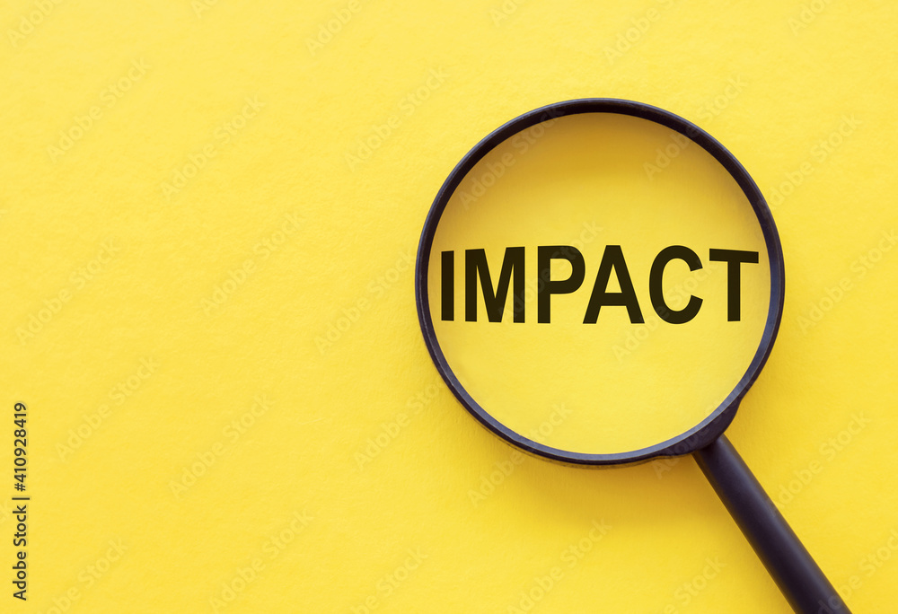 The word IMPACT is written on a magnifying glass on a yellow background. The word IMPACT is written on a magnifying glass on a yellow background.