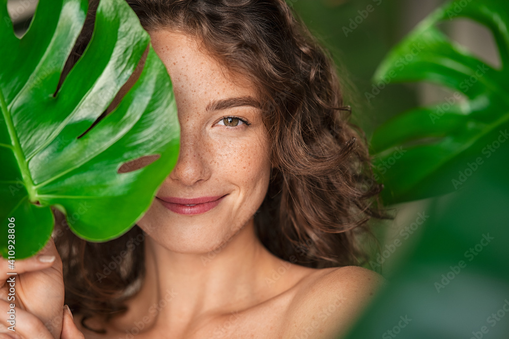 Beauty natural woman covering her face with tropical leaf - obrazy, fototapety, plakaty 