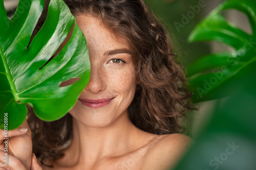Beauty natural woman covering her face with tropical leaf