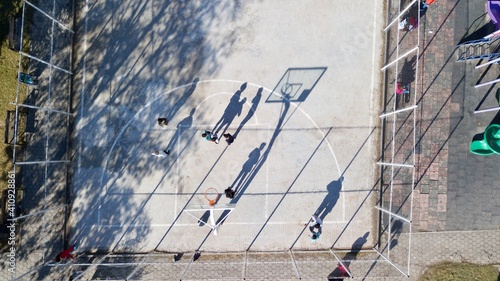 aerial view of street basketball court and children playground. kids are playing football at the sunset.