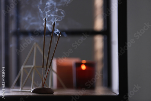 Fotografi Incense sticks smoldering on shelf indoors, space for text