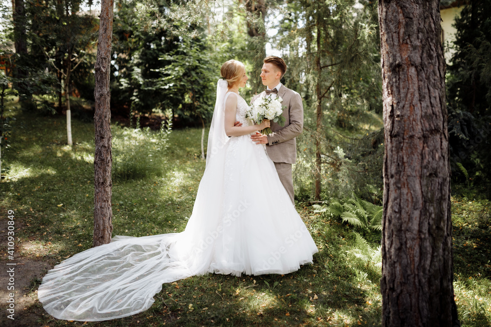 luxury stylish young bride and groom on the background spring sunny green forest. Couple in love luxury stylish young bride and groom on the background spring sunny green forest. Couple in love