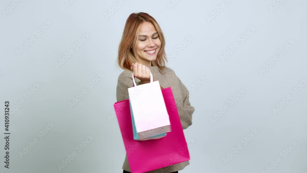 Teenager girl holding shopping bags with the arms crossed while smiling over isolated background Teenager girl holding shopping bags with the arms crossed while smiling over isolated background