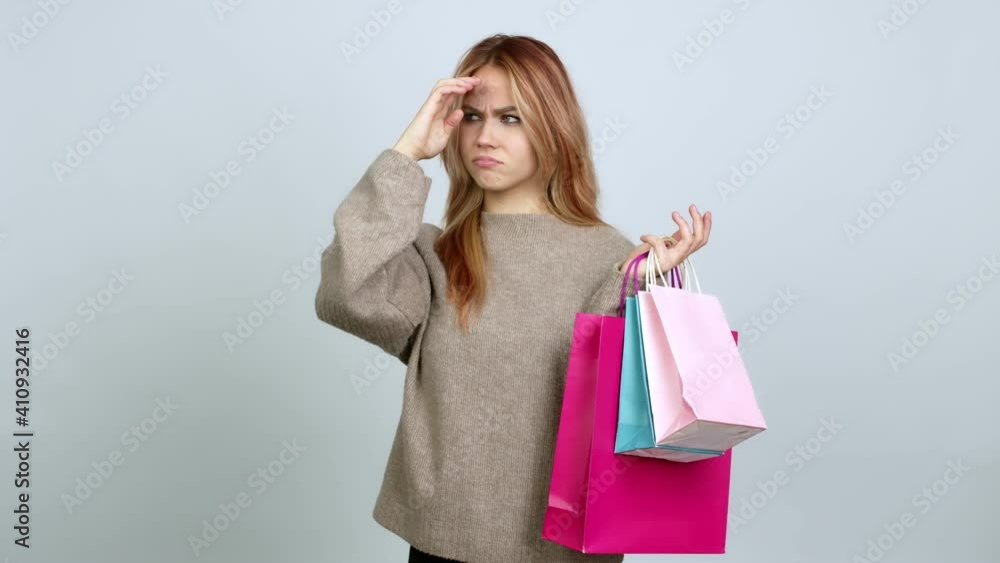 Teenager girl holding shopping bags having doubts while scratching head over isolated background Teenager girl holding shopping bags having doubts while scratching head over isolated background