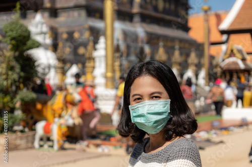 Close-up portrait of woman wearing a mask to prevent the coronavirus in a temple in northern Thailand.