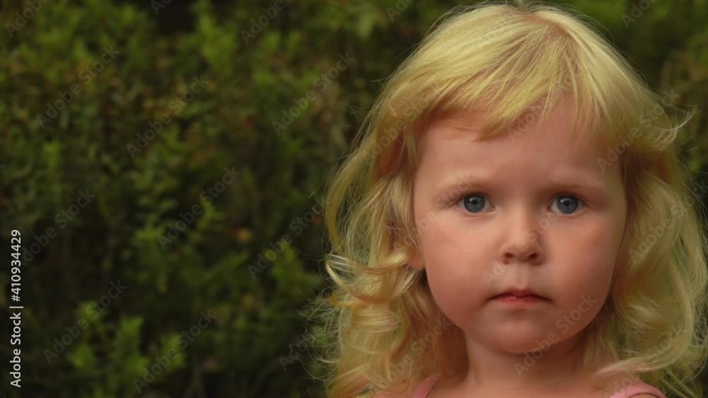 Beautiful little blond girl is looking up in the sky in amazement outdoors at the garden Beautiful little blond girl is looking up in the sky in amazement outdoors at the garden