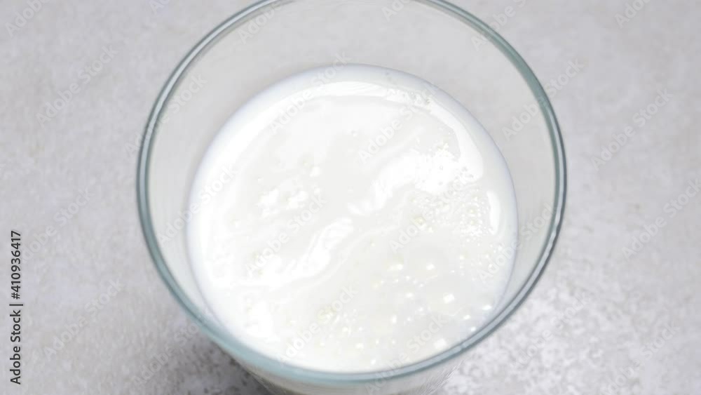 Slow motion shot of pouring, splashing fresh milk into a transparent glass against white background. Dairy product concept. Filling glass with milk close up Slow motion shot of pouring, splashing fresh milk into a transparent glass against white background. Dairy product concept. Filling glass with milk close up