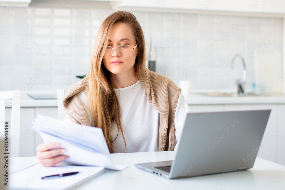 Photo of a woman in front of laptop monitor working with papers. Photo of a woman in front of laptop monitor working with papers.