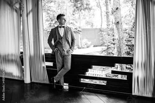 Stylish young man in a business suit.Handsome groom posing. Groom in suit posing by the window.