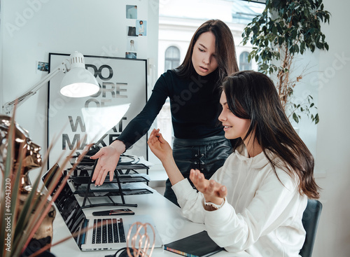 Expressive manager and office worker discuss their plans at desktop in office room.