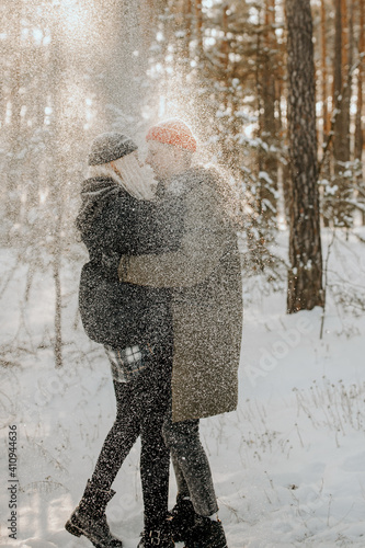 Young couple playing with snow and kissing and hugs