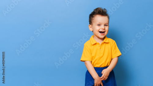 Portrait of a cute laughing little boy on a blue background. Copy space.