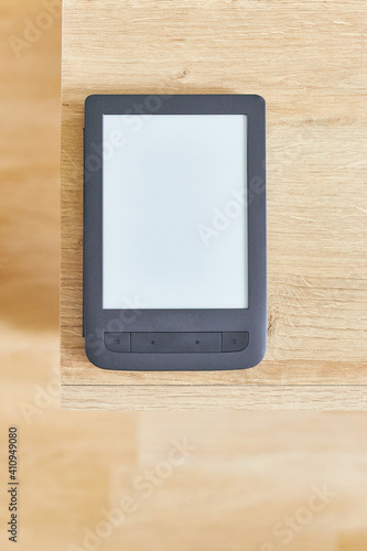 black electronic book with empty screen on wooden table and free space for advertise text top view. Vertical shot