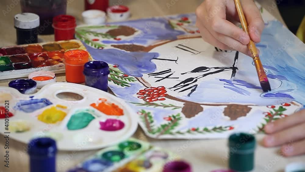 The boy draws a New Years drawing on paper with multi-colored paints. Christmas poster, teaching drawing, home art, fine arts school The boy draws a New Years drawing on paper with multi-colored paints. Christmas poster, teaching drawing, home art, fine arts school