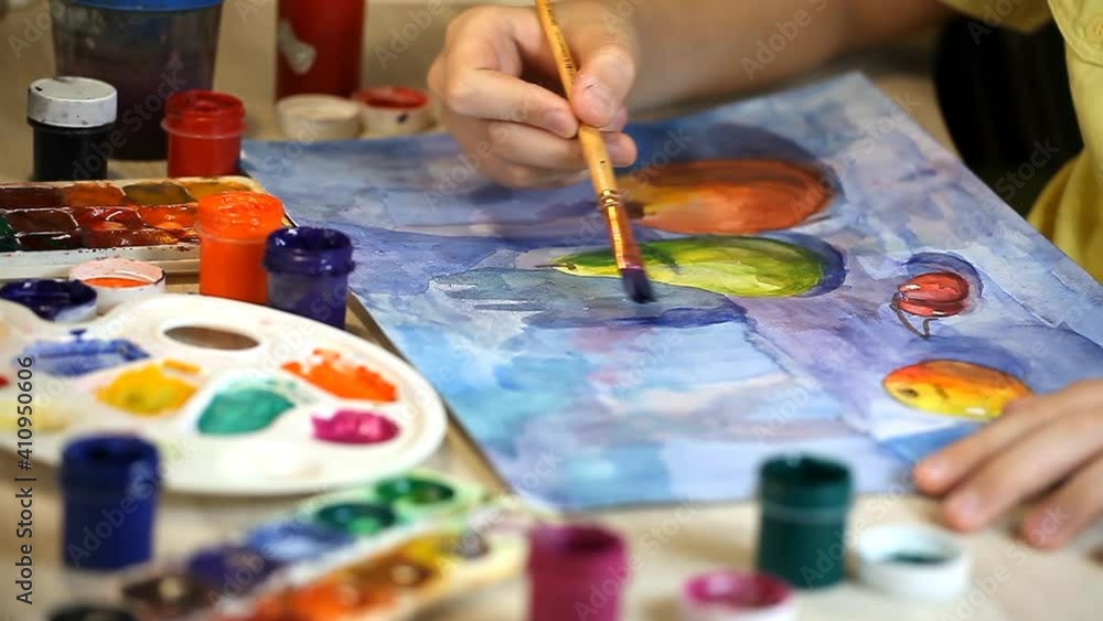 The boy draws with gouache on paper. Online painting lesson during a pandemic. Drawing at home, classes during self-isolation. Life during COVID-19