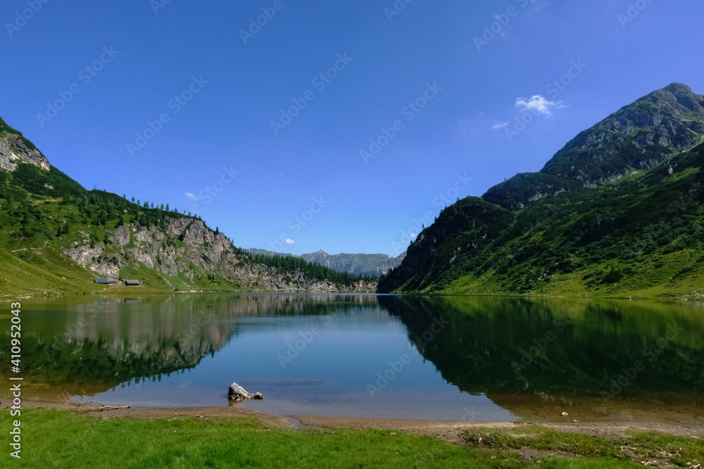 standing on the shore from a blue mountain lake with wonderful reflection from the landscape