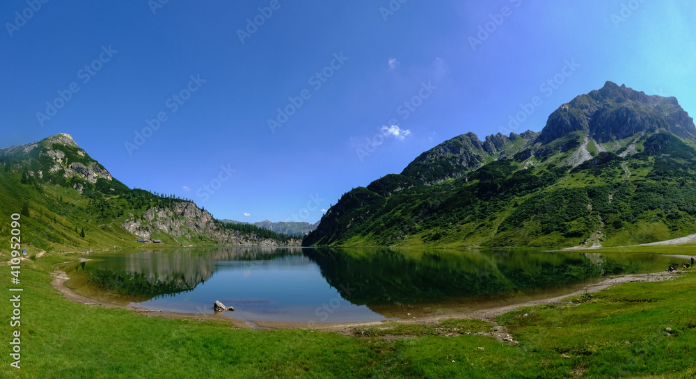 standing on the shore from a blue mountain lake with wonderful reflection from the landscape panorama