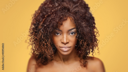  Beautiful black woman . Beauty portrait of african american woman with clean healthy skin on beige background. Smiling beautiful afro girl.Curly black hair