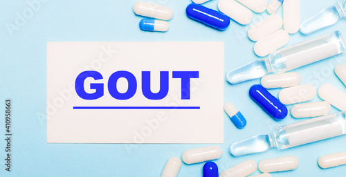 Pills, ampoules and a white card with the text GOUT on a light blue background. Medical concept