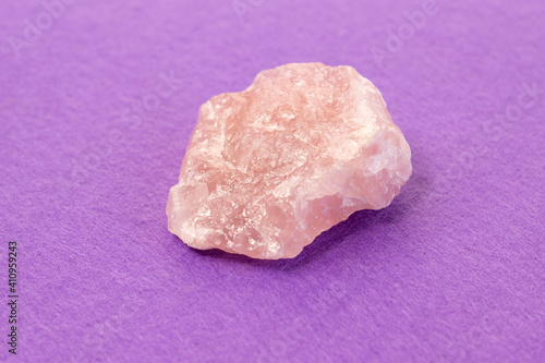 Piece of polished pink quartz on purple background. Minimal color still life Narrow focus line, shallow depth of field