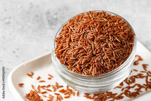Red rice in a glass bowl on the light gray kitchen table. Red rice on a light background