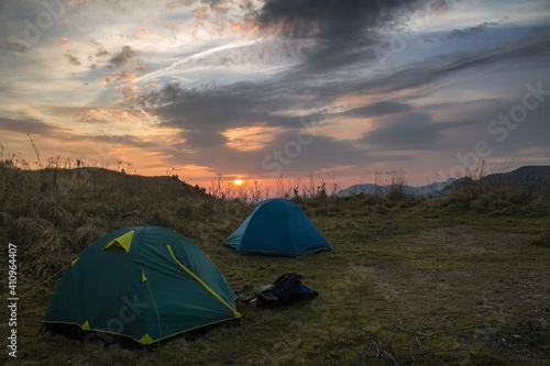 Tourist campground in the mountains in a meadow during sunrise. Hiking tour in the mountains.
