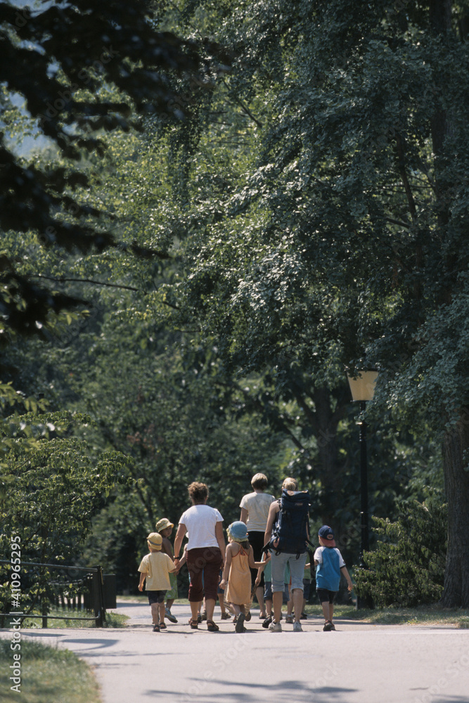 Fototapeta premium Drei Frauen gehen mit Kindern durch einen Park