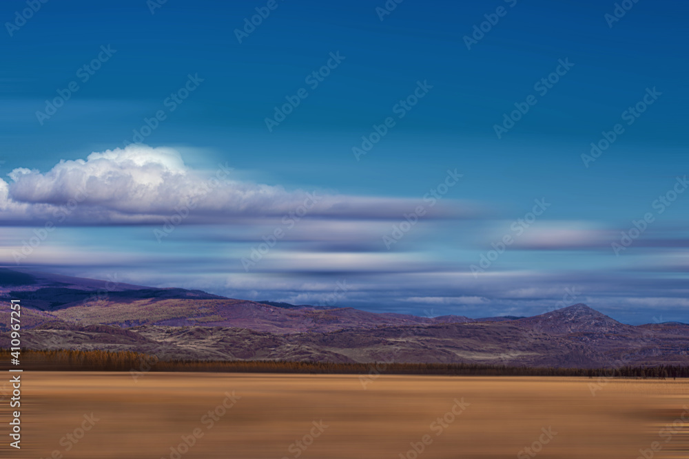 panoramic view of plain at root of snow-covered mountains on blue sky background panoramic view of plain at root of snow-covered mountains on blue sky background