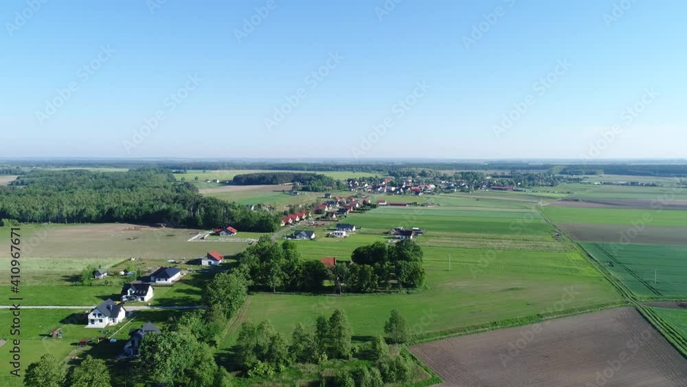 Polish countryside landscape. Green cultivated fields and meadows seen from the bird's eye view. Numerous rural buildings stretching along the road. Beautiful sunny day with a blue sky. Polish countryside landscape. Green cultivated fields and meadows seen from the bird's eye view. Numerous rural buildings stretching along the road. Beautiful sunny day with a blue sky.