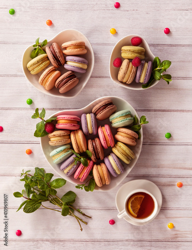 Colorful macaroni cakes. Small French cakes. Sweet and colorful French macarons are plates in the shape of a heart. Top view