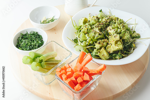 Fresh mix salad with avocado and sauce on a round wood rotating tray. Healthy orgaic salad of iceberg, avocado and cucumber with olive oil,  microgreen, celery and sesame seeds.   photo