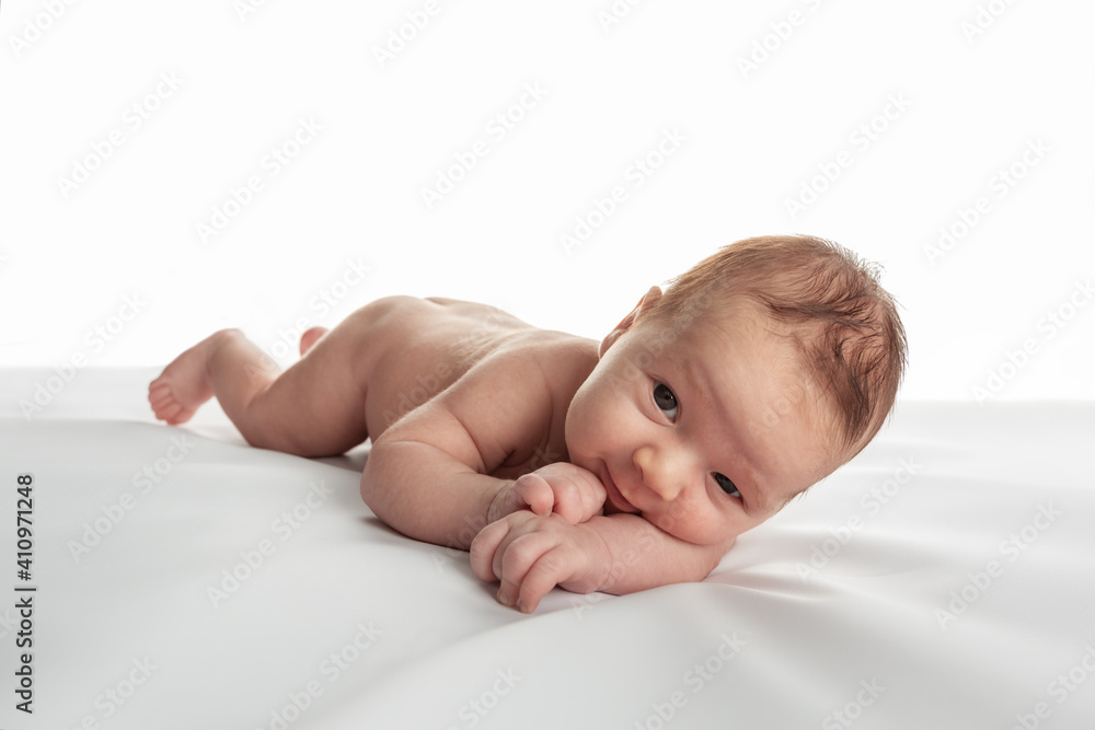 Funny little caucasian toddler lying on the light plaid in front of the white background. Funny little caucasian toddler lying on the light plaid in front of the white background.