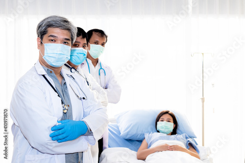 Professional doctor team of Asian man, wearing a surgical mask To prevent the spread of germs or virus, ready to care and treatment the patient, with blur patient woman background, health care concept