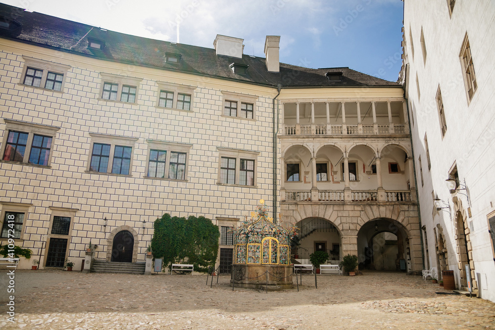 Courtyard of medieval castle and chateau, historical palace complex, arcades and white renaissance archs with ornamental water well, Jindrichuv Hradec, South Bohemia, Czech Republic