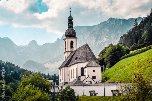 Amazing alpine landscape in the Bavarian Alps with the church of St. Sebastian in the national park Berchtesgaden. The church is standing in a valley surrounded by forested hills and rough mountains.