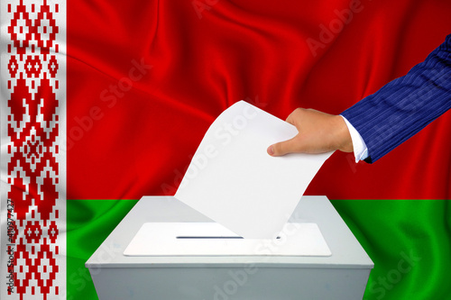 Elections in the country - voting at the ballot box. A man's hand puts his vote into the ballot box. Flag Belarus on background. photo