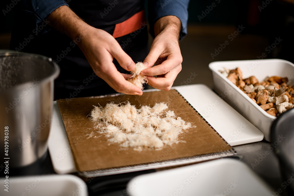 close-up of hands of male chef who lays ingredients for dish on cutting board
